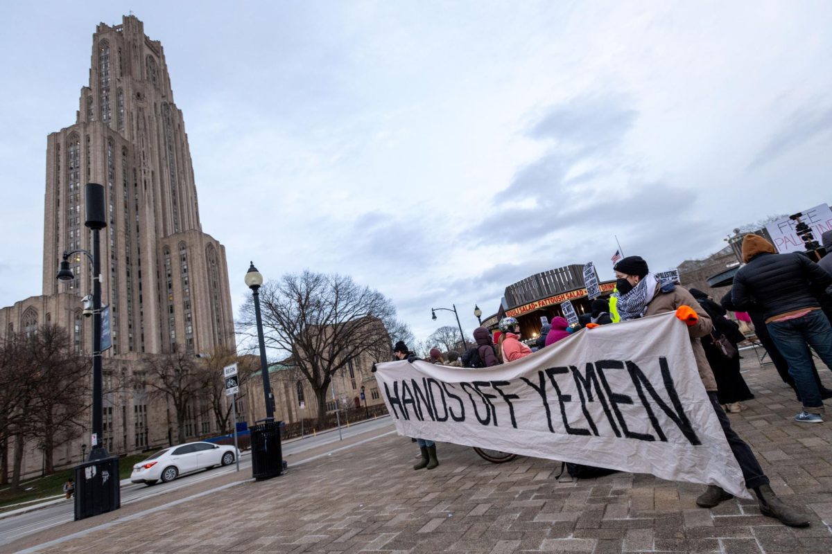 Protesters hold a banner during Monday afternoon’s “Hands Off Yemen” protest in Schenley Plaza.