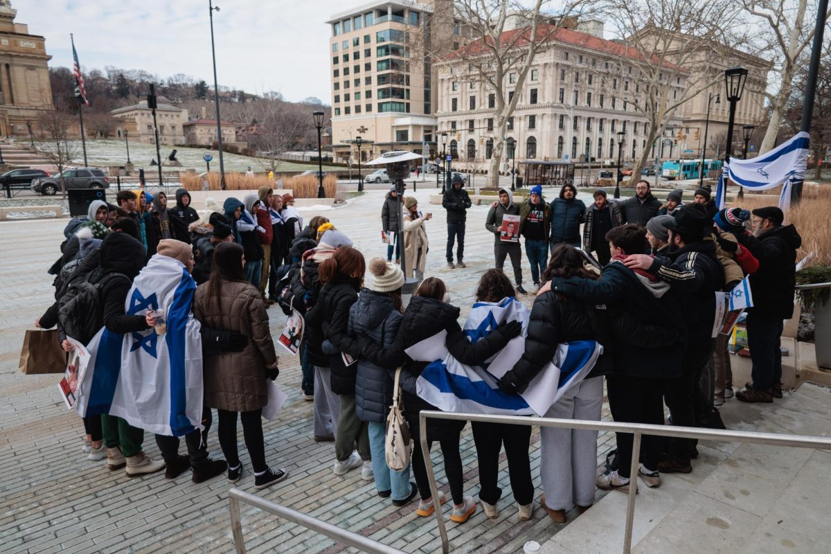 “Bring Them Home” vigil attendees join arms and sing Hatikvah, the Israeli national anthem, on Monday afternoon on the WPU Plaza.