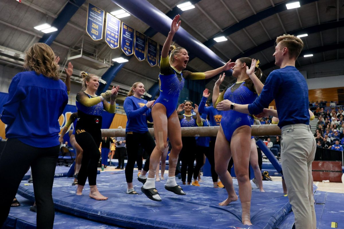 Pitt gymnastics team members celebrate after a beam routine during Saturday’s meet against the Kent State Gold Flashes at the Fitzgerald Field House.