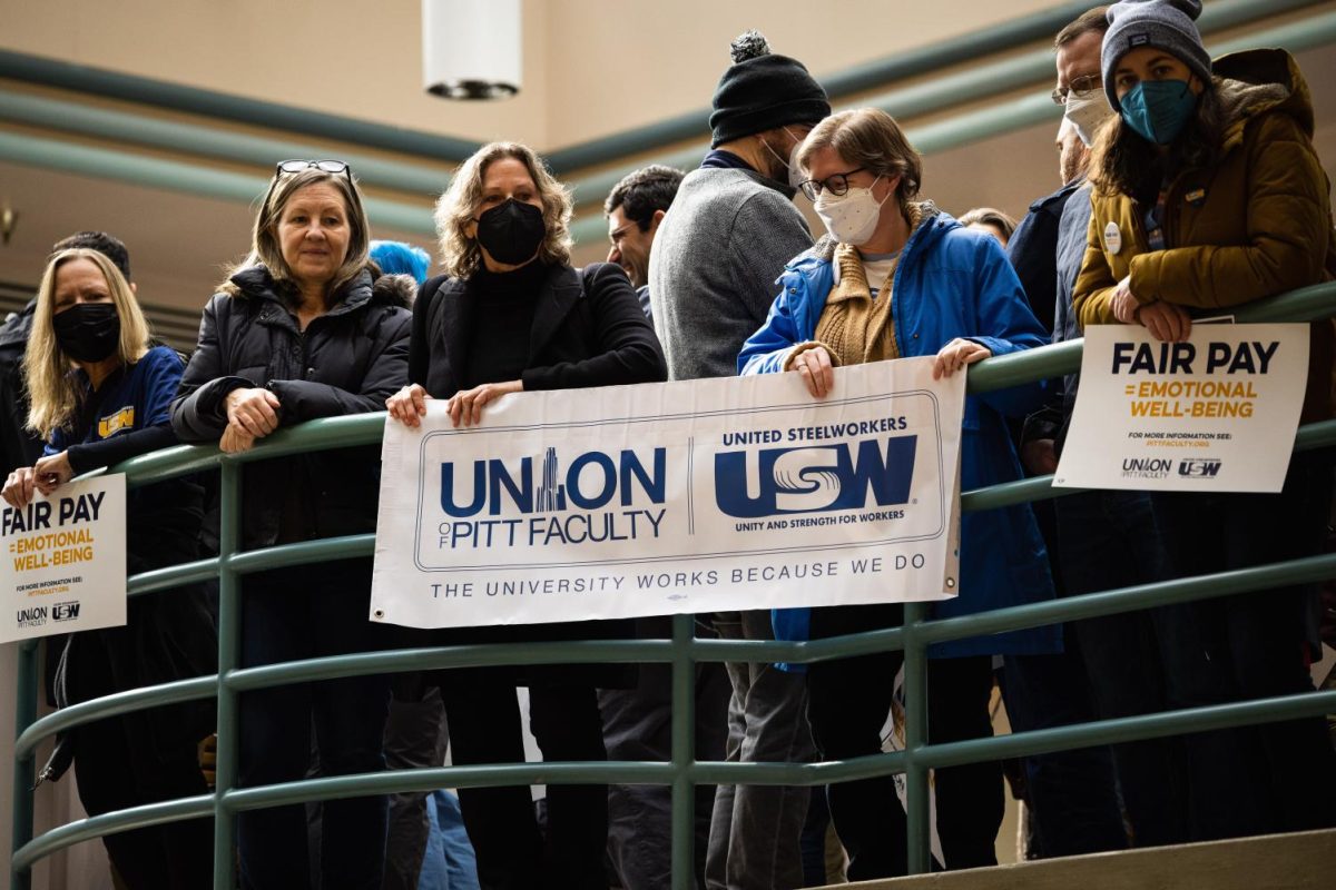 Supporters of the faculty union hold signs inside of the William Pitt Union to protest the Board of Trustees meeting on Feb. 24, 2023.