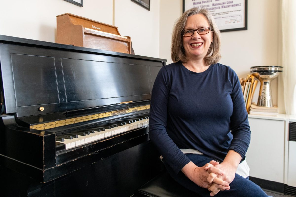 Amy Williams sits at a piano in their office.