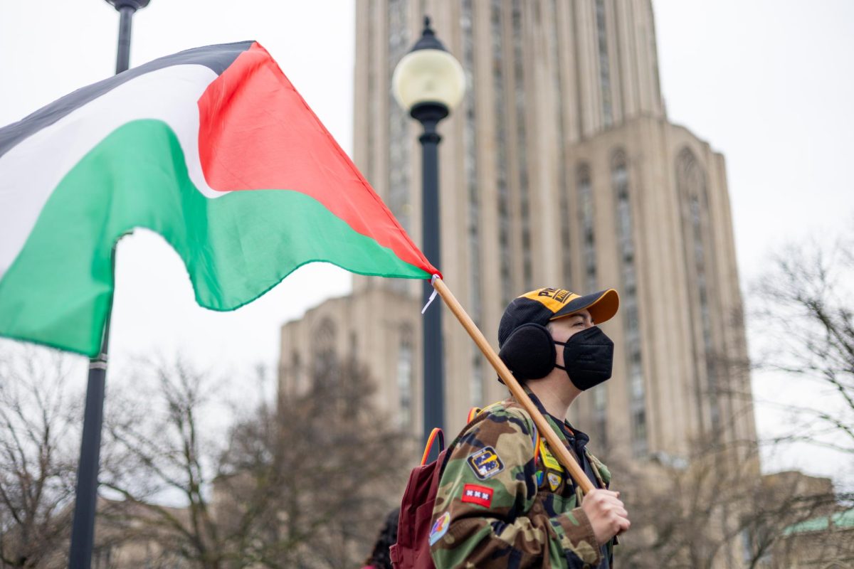 A protester waves a Palestinian flag in front of the Cathedral of Learning during Saturday’s Land Day protest in Schenley Plaza. (Bhaskar Chakrabarti | Staff Photographer)
