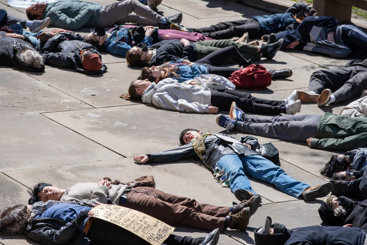 Protesters participate in a die-in in front of the Cathedral of Learning on Friday at an event hosted by Pittsburgh Palestine Coalition. (Liam Sullivan | Staff Photographer)