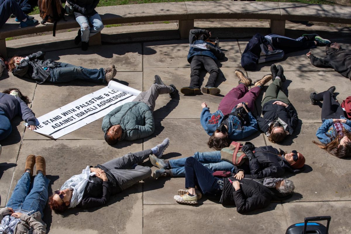 Protesters participate in a die-in in front of the Cathedral of Learning on Friday at an event hosted by Pittsburgh Palestine Coalition. (Liam Sullivan | Staff Photographer)