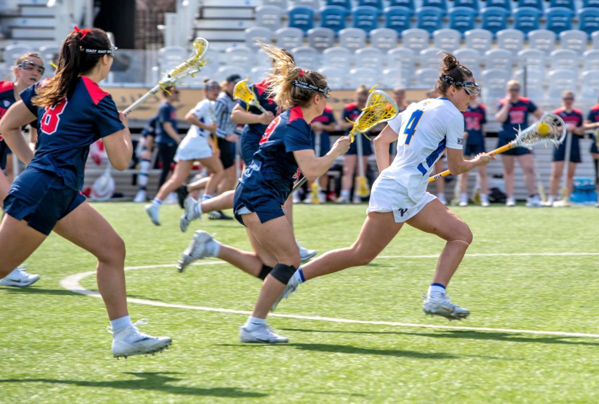 Senior midfielder Emily Coughlin (4) runs with the ball during a lacrosse game against Detroit Mercy at Highmark Stadium on Feb. 26.