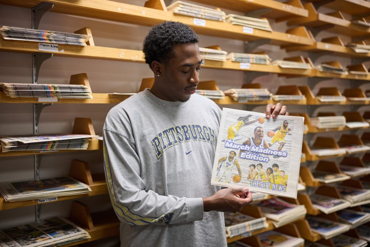 Jermaine Sykes, assistant sports editor, poses for a photo with a copy of The Pitt News March Madness Edition.