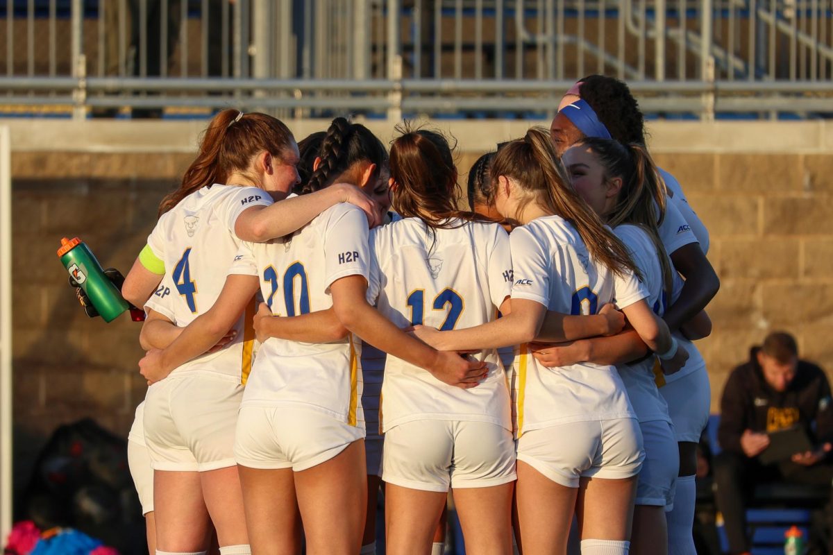 Pitt women’s soccer team huddles during Saturday evening’s game against West Virginia on Saturday evening at Ambrose Urbanic Field.