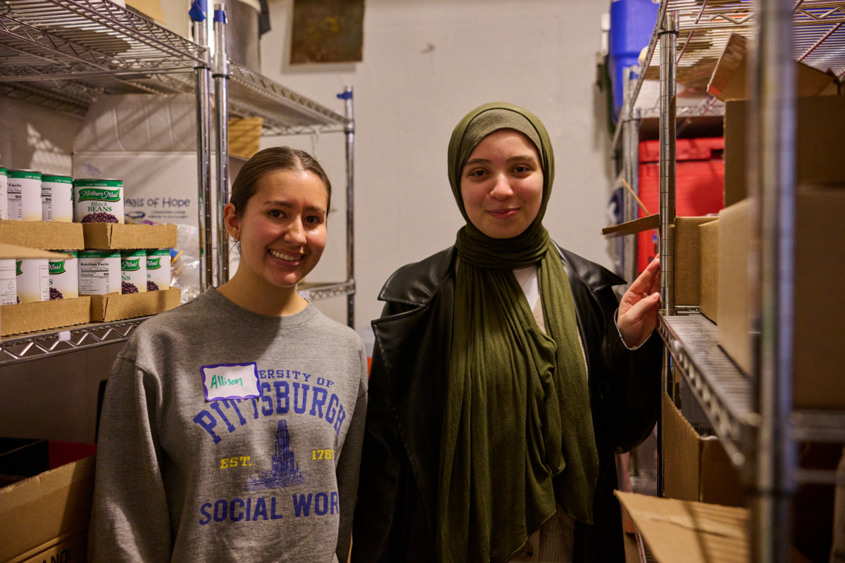 Junior social work major Allison Butterfield (left) and sophomore neuroscience major Malak Ayoub (right) pose for a photo in the stockroom of the Islamic Center of Pittsburgh Food Pantry.