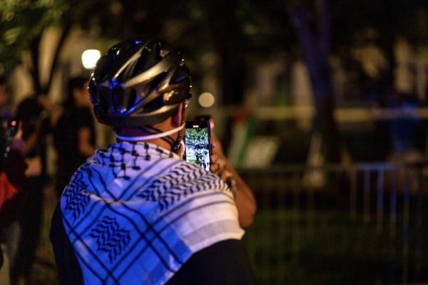 A protester records an interaction between police and protesters at the Palestine Solidarity Encampment on Sunday night.
