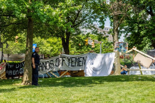 Police officer stands tensely in front of a “HANDS OFF YEMEN” sign at the Palestine solidarity encampment on Monday, June 3.
