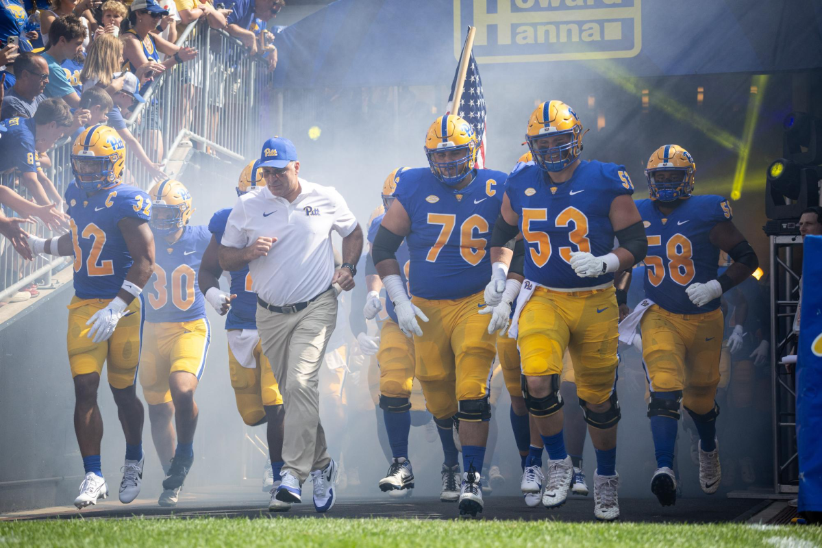 The Pitt Football team runs onto the field with Head Coach Pat Narduzzi.