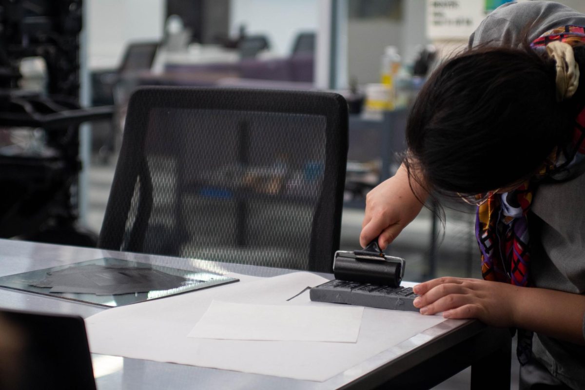 A student rolls ink onto a stamp at the East Asian Printing and Bookbinding event in Hillman Library on Tuesday, Sept. 17.
