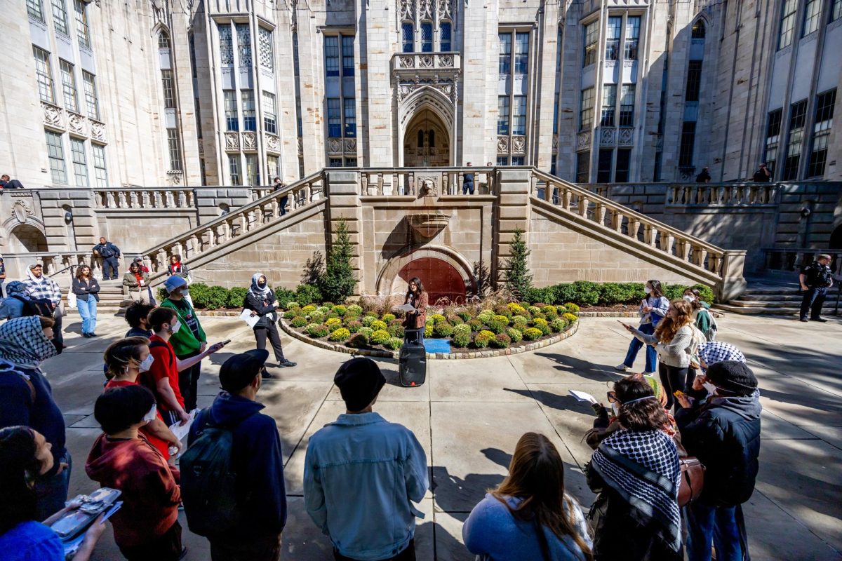 Attendees listen to a speaker at the Teach In, Walk Out for Divestment in front of the Cathedral of Learning on Thursday.
