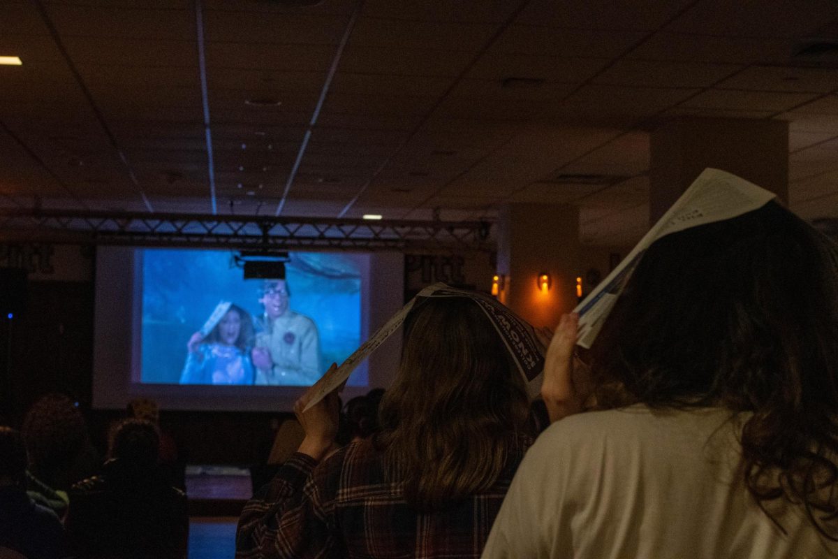 Attendees watch Rocky Horror Picture Show with newspapers on their heads in Nordy’s Place on Friday, Oct. 25.
