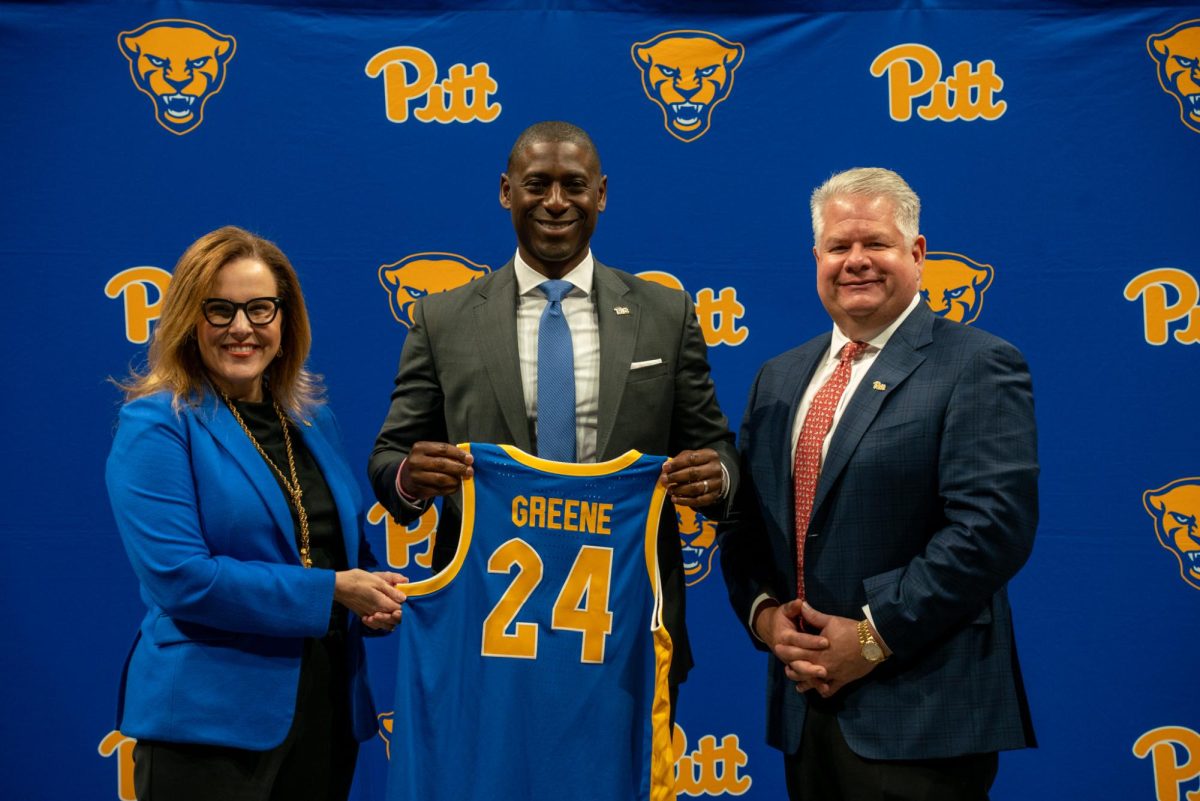 New Athletic Director Allen Greene, Pitt Chancellor Joan Gabel and Pitt Board of Trustees Chairperson John Verbanac pose for a photo with a custom Pitt men’s basketball jersey during a press conference on Wednesday, Oct. 23, 2024.