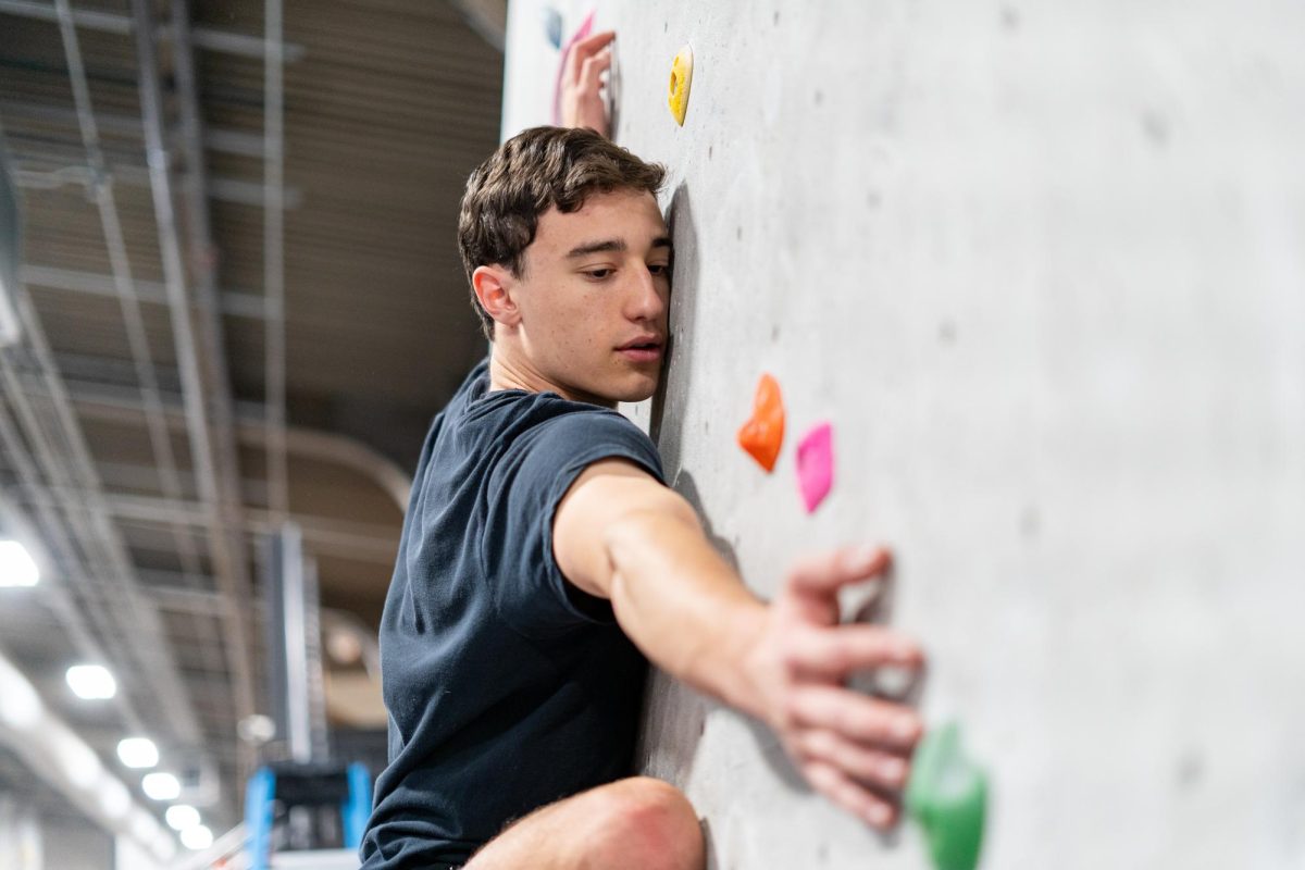 A member of the Club Climbing Team reaches for a hold.