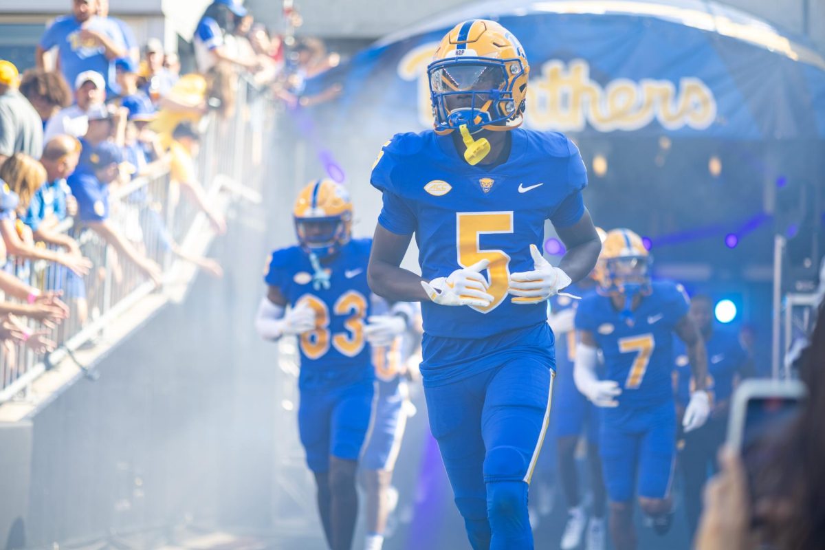 Redshirt junior wide receiver Raphael Williams Jr. (5) runs onto the football field alongside his teammates.
