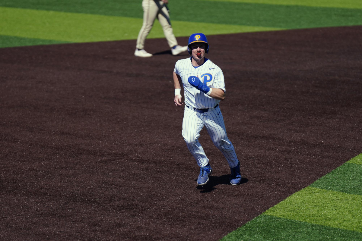 A Pitt player runs to third base during a baseball game.
