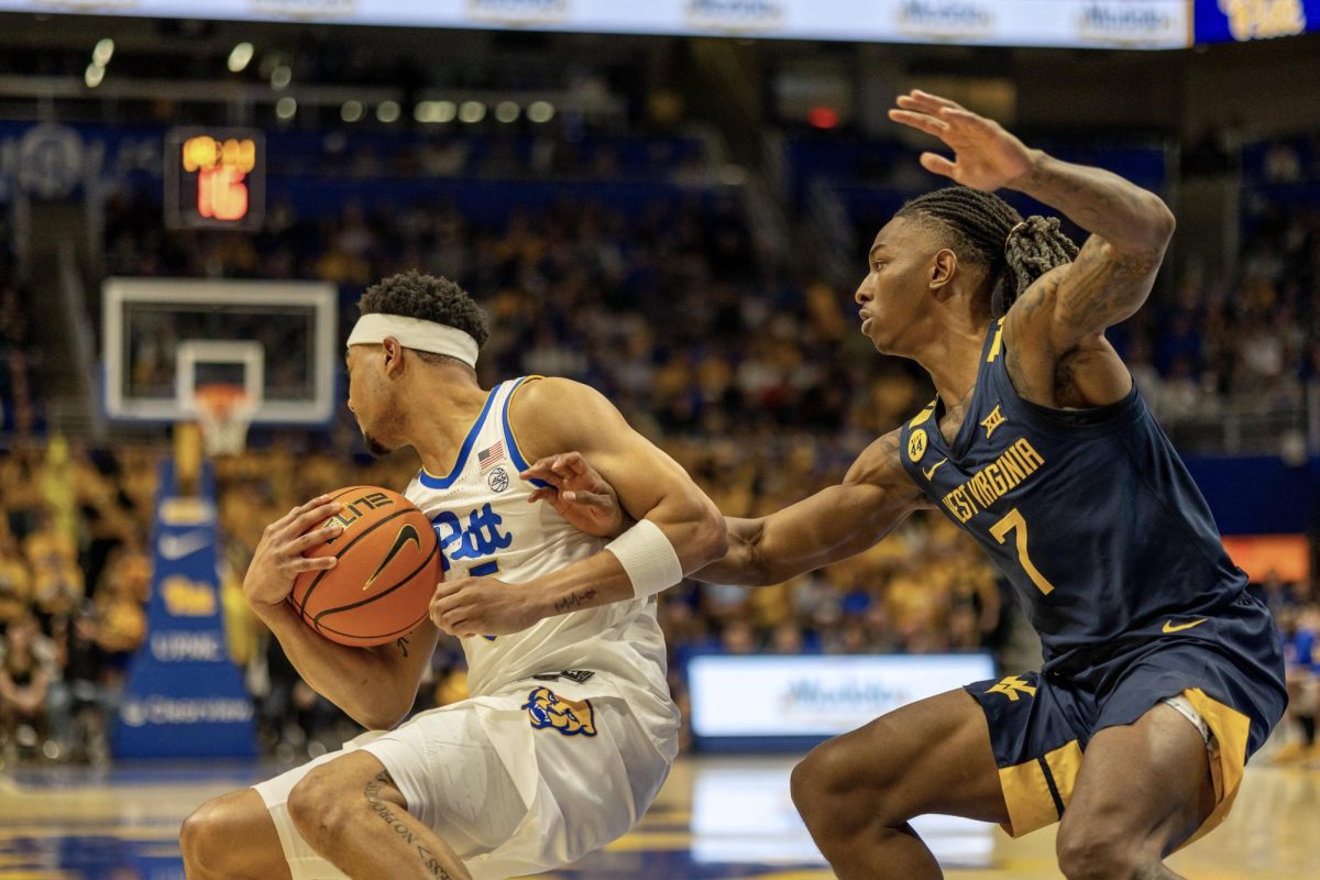 A West Virginia player attempts to block senior guard Ishmael Leggett (5) during the Pitt men's basketball game against West Virginia in the Petersen Events Center on Friday, Nov. 15.
