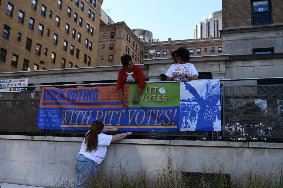 Pitt Votes representatives hang a sign outside the William Pitt Union on Tuesday, Nov. 5.
