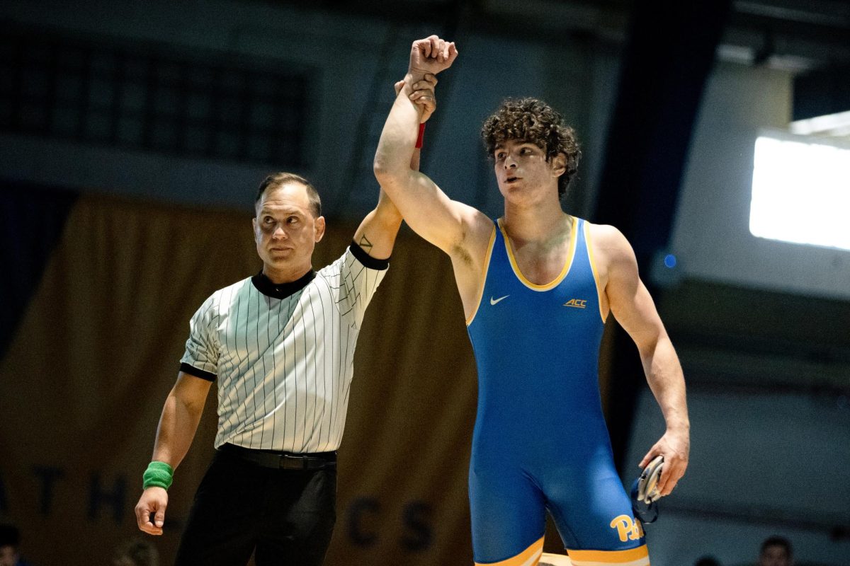 A referee holds up the hand of a Pitt wrestler at the match in the Fitzgerald Field House on Sunday, Nov. 3.