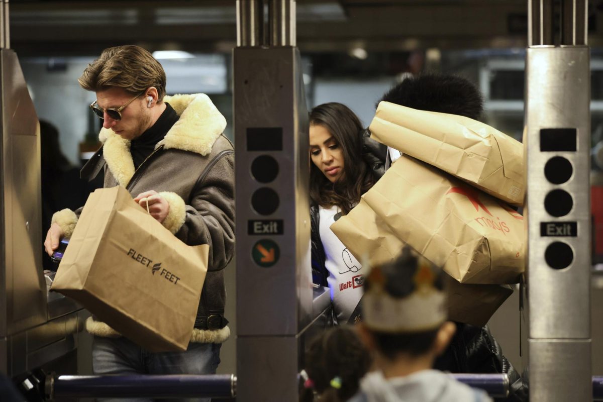 Shoppers manage their bags as they enter a Subway turnstile, Friday, Nov. 29, 2024, in New York.