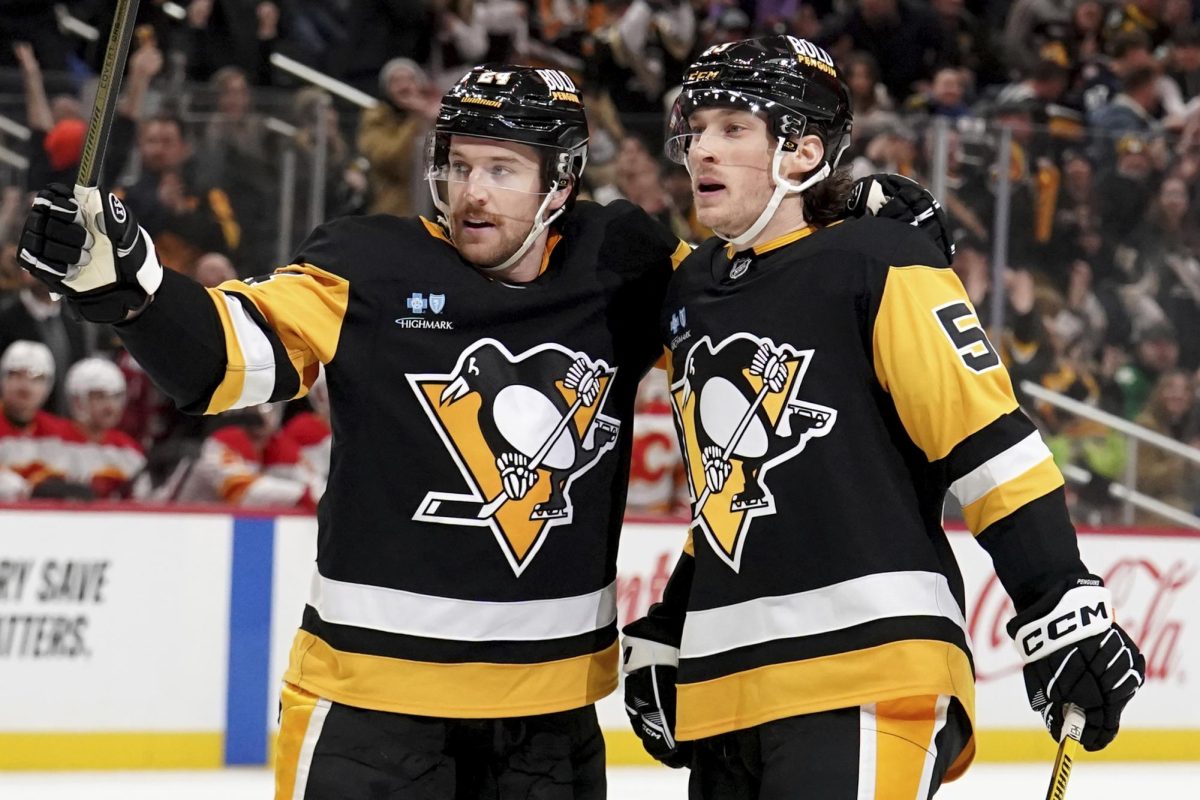 Pittsburgh Penguins' Philip Tomasino, right, celebrates with Matt Grzelcyk, left, after scoring during the second period of an NHL hockey game against the Calgary Flames, Saturday, Nov. 30, in Pittsburgh.