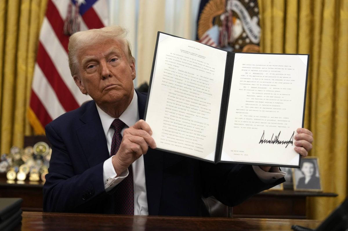 President Donald Trump signs an executive order relating to cryptocurrency in the Oval Office of the White House, Thursday, Jan. 23, 2025, in Washington.