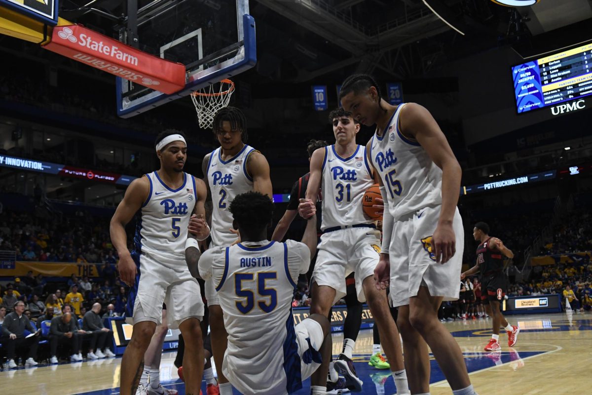 Pitt men’s basketball players help redshirt senior forward Zach Austin (55) to his feet during Pitt men’s basketball’s game against Stanford at the Petersen Events Center on Saturday, Jan. 5.