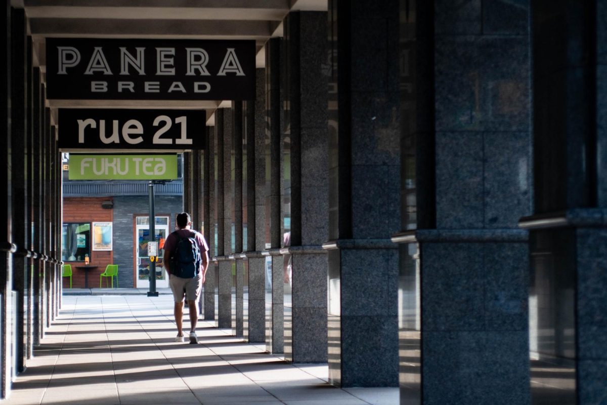 A student with a backpack walks outside of Panera Bread on Forbes Avenue.