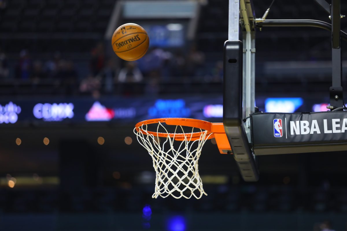 A basketball is shot towards an NBA basketball hoop.
