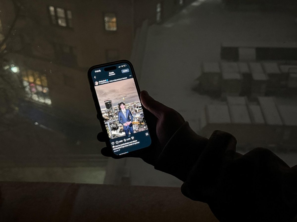 A student holds a phone with Clavicular’s Instagram account. 
